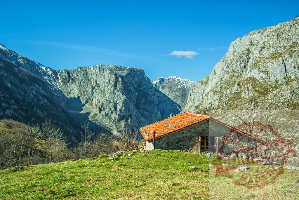 Stone cabin in Picos de Europa mountain landscape | Rustic stone dwelling with orange roof nestled in a green mountain valley - Realized with Pictrs.com
