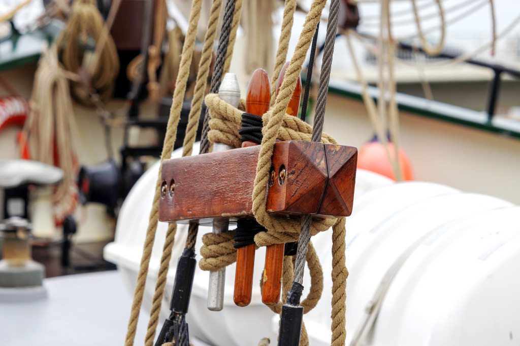 Wandbild: Segelboot-Detail mit Tauwerk in Kappeln | Dieses Wandbild im Querformat zeigt eine Detailaufnahme eines Segelboots im Hafen von Kappeln. Im Mittelpunkt steht ein hölzerner Block mit kunstvoll geführtem Tauwerk und metallischen Beschlägen – ein Sinnbild für traditionelles Handwerk und nautische Präzision. Die Szene vermittelt die stille Kraft des Segelns und die Schönheit maritimer Technik. Ideal für Wohnräume, maritime Geschäftsräume oder Ferienunterkünfte mit Küstenflair. Erhältlich als Leinwand, Acrylglas, Alu-Dibond, hochwertiger FineArt-Druck oder als schallabsorbierendes Akustikbild. - Realisiert mit Pictrs.com