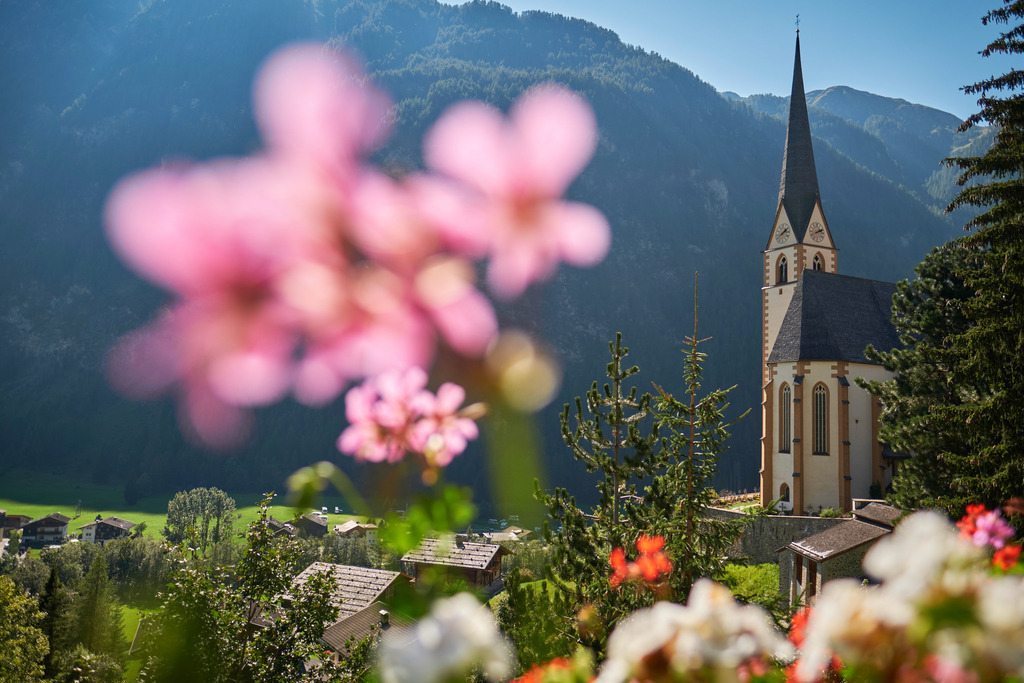 Wallfahrtskirche St. Vinzenz in Heiligenblut | Heiligenblut, Austria - September 15, 2020: Wallfahrtskirche St. Vinzenz in Heiligenblut mit Blumen im Vordergrund. - Realisiert mit Pictrs.com