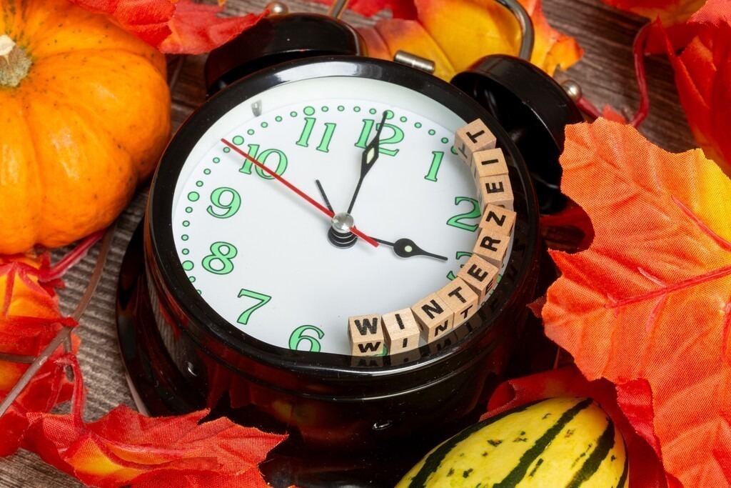Zeitumstellung Winterzeit: Nahaufnahme von einem Wecker, herbstlicher Dekoration und Buchstabenwürfeln die das Wort WINTERZEIT anzeigen | Zeitumstellung Winterzeit: Nahaufnahme von einem Wecker, herbstlicher Dekoration und Buchstabenwürfeln die das Wort WINTERZEIT anzeigen - Realisiert mit Pictrs.com