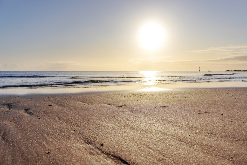 Wandbild: Sonnenaufgang an der Ostsee | Dieses Wandbild im Querformat zeigt einen schönen Sonnenaufgang an der Ostsee. Im Vordergrund befindet sich der Sandstrand, der durch das morgendliche Sonnenlicht schön angeleuchtet wird. Am Horizont ist der blaue Himmel noch dezent gelblich. - Realisiert mit Pictrs.com