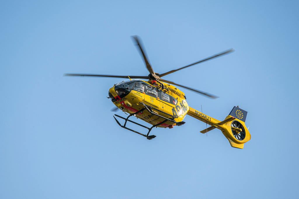 ADAC Rettungshubschrauber | Ein markanter gelber ADAC-Rettungshubschrauber (Christoph 1) fliegt mit rotierenden Blättern durch ein strahlendes, wolkenloses Blau. Die dynamische Untersicht betont die technische Eleganz und die ständige Einsatzbereitschaft der Luftretter. - Realisiert mit Pictrs.com