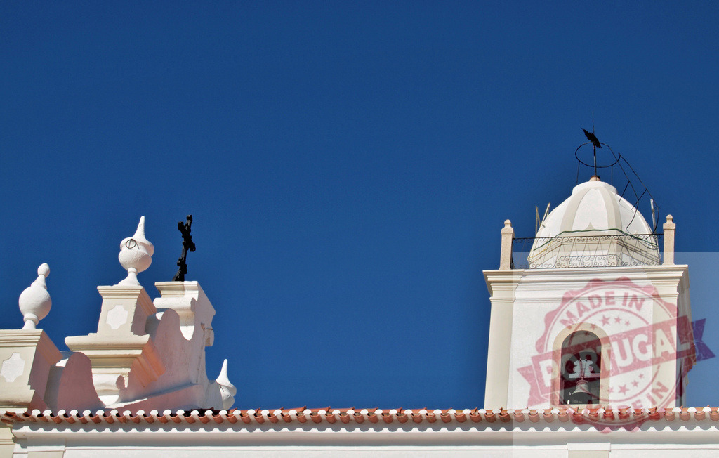 Bell tower and rooftop details of a historic church | White bell tower and ornate rooftop against a clear blue sky, showing traditional Portuguese architecture - Realisiert mit Pictrs.com