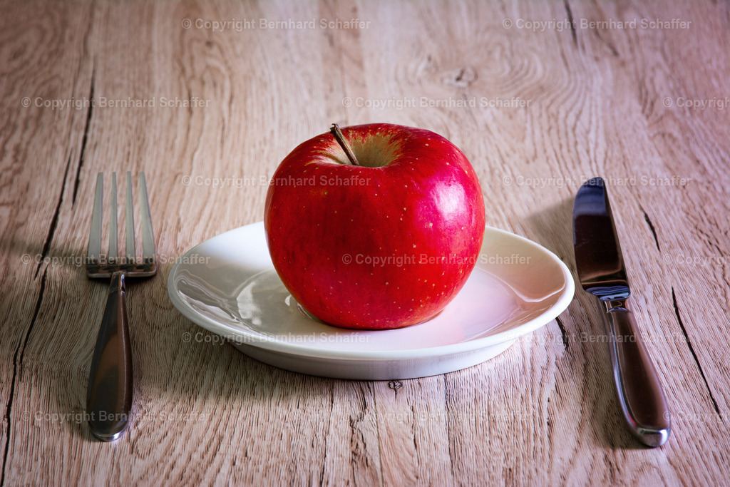 Apfel auf Teller | Ein Apfel liegt auf einem Teller und Besteck. - Realisiert mit Pictrs.com