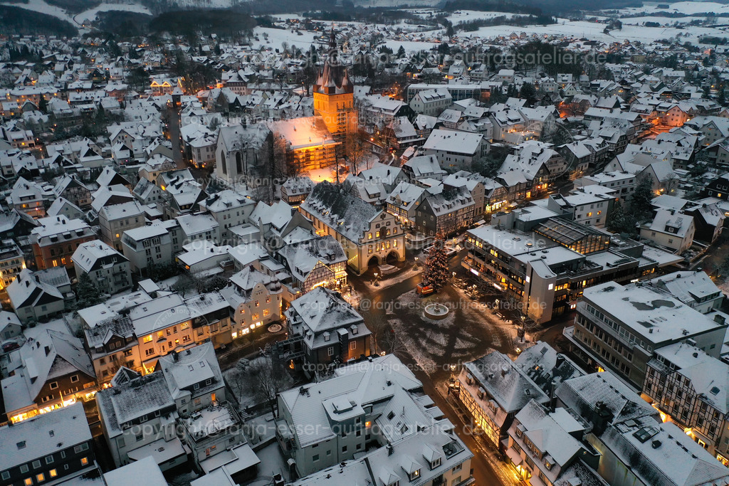 Vogelperspektive zeigt verschneite Briloner Innenstadt mit Propsteikirche | Luftbild zeigt den Briloner Marktplatz an einem Winterabend. Stimmungsvolles winterliches Bild des beleuchteten Stadtzentrums im Schnee.