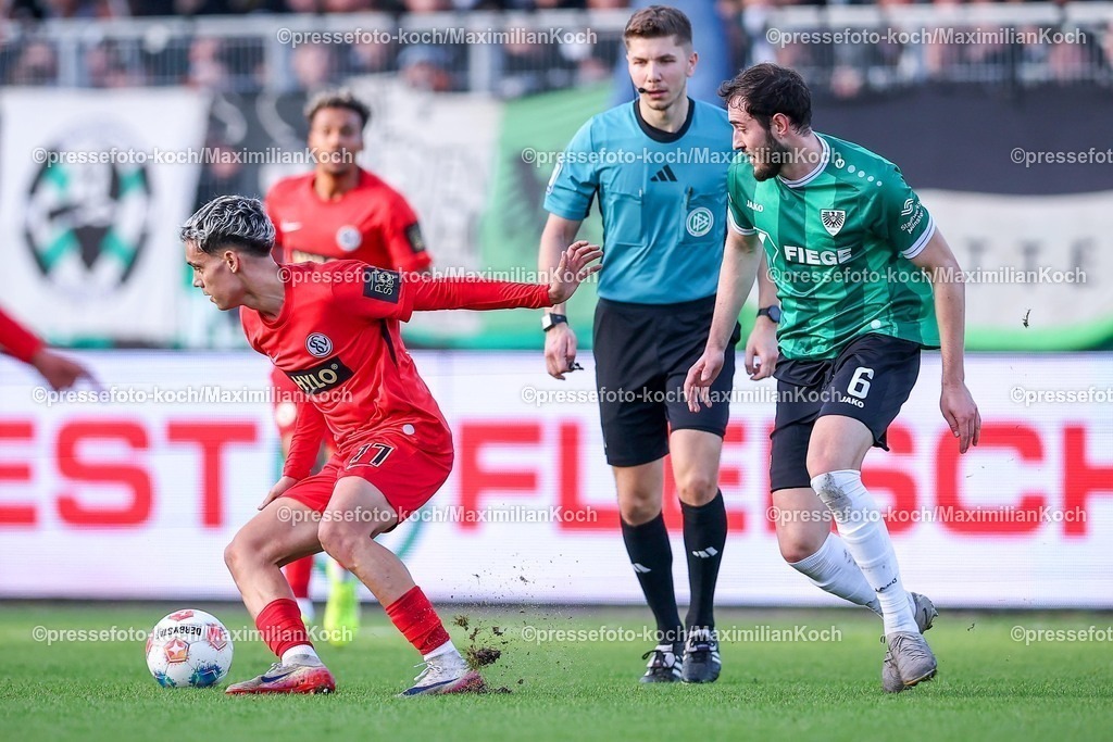 PRM21122501046 | 21.12.2025, Fußball, Preußen Münster - SV 07 Elversberg, 2. Fußball Bundesliga,  Preußenstadion, 17.Spieltag, Saison 2025 2026: Frederik Schmahl (Elversberg #17) neben Schiedsrichter Felix Wagner und Marcel Benger (Preussen Muenster #06)  DFB regulations prohibit any use of photographs as image sequences and or quasi-video.