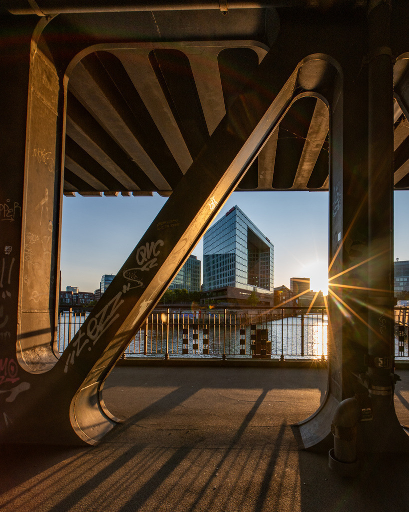 Spiegel-Verlagsgebäude im Abendlicht unter der Oberhafenbrücke | Gerahmter Blick unter der Oberhafenbrücke auf das SPIEGEL-Verlagsgebäude an der Ericusspitze im warmen Abendlicht. - Realisiert mit Pictrs.com