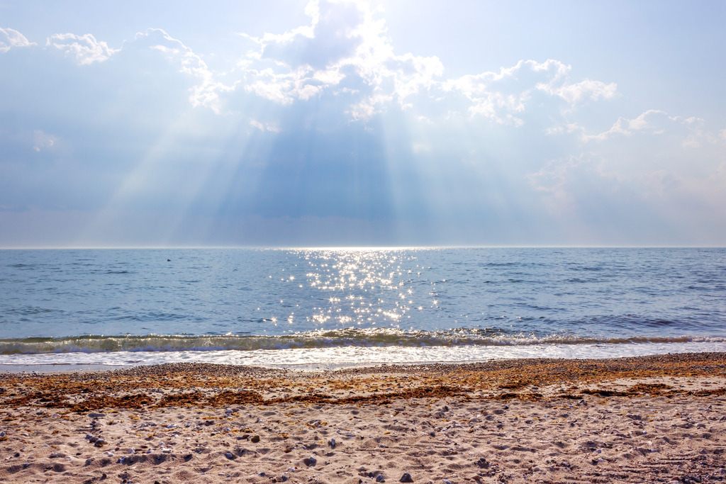 Wandbild: Ostsee-Lichtspiel über der Weite | Lass den Alltag hinter dir und spüre die Weite des Meeres, während goldene Lichtbahnen durch die Wolken brechen und die Ostsee in ein funkelndes Licht tauchen. Dieses Motiv fängt den flüchtigen, magischen Moment ein, in dem die Sonne das Wasser zum Glitzern bringt und eine Atmosphäre von tiefer Ruhe und Hoffnung schafft. Hol dir das unvergleichliche Gefühl eines klaren Tages am Meer direkt in dein Wohnzimmer und schaffe einen Rückzugsort voller Inspiration. - Realisiert mit Pictrs.com