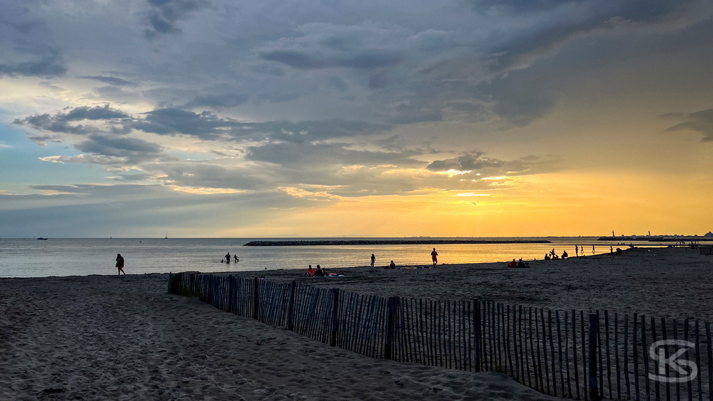 Malerischer Sonnenuntergang am Sandstrand der Camargue – Südfrankreich | Weite Sandstrände der Camargue mit charakteristischen Ganivelles-Holzzäunen und sanften Wellen im goldenen Sonnenuntergang an der Mittelmeerküste. - Realisiert mit Pictrs.com