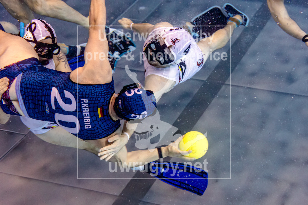 Deutsche Meisterschaft 2024 in Unterwasser-Rugby | Vorrundenspiel: Tauchclub Bamberg in weiß gegen DUC Krefeld in blau. Der Bamberger Lukas Tadda (Nummer 4) fängt den Krefelder Angreifer Phillip Kreißig (Numme 20) ab. - Realisiert mit Pictrs.com