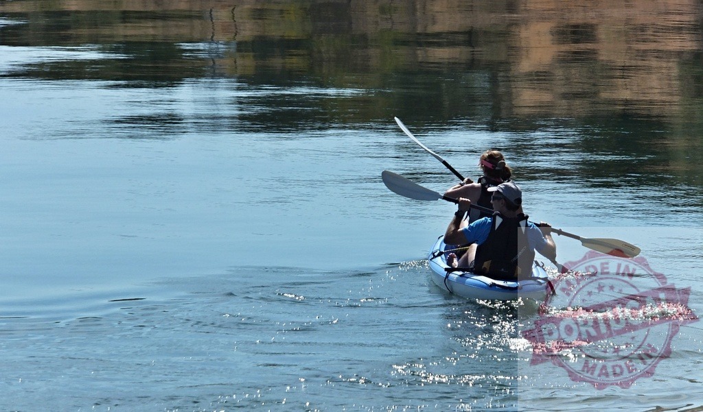 Couple kayaking on river enjoying active outdoor recreation | Two people paddling an inflatable kayak on calm water, creating ripples - Realisiert mit Pictrs.com