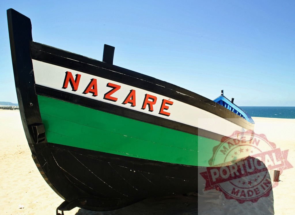Traditional multicolored fishing boat from Nazaré on sand beach | Old fishing boat with Nazaré written on bow staying on a sand beach - Realized with Pictrs.com