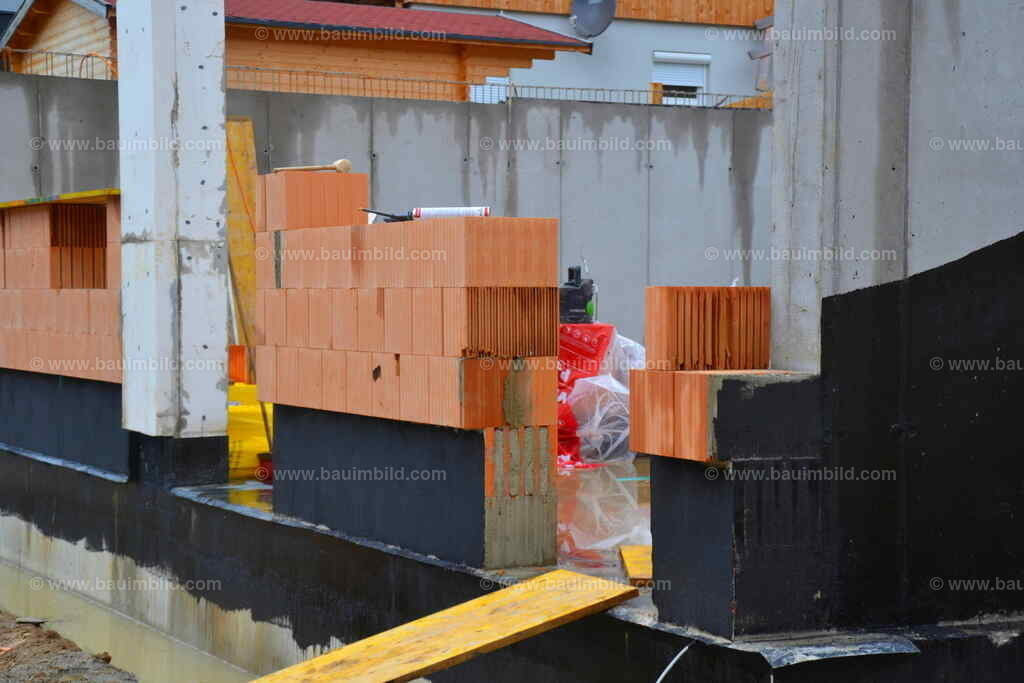 Isolierung Mauersockel | Ziegelmauerwerk auf Bodenplatte, mit schwarzem Bitumenanstrich im Sockelbereich