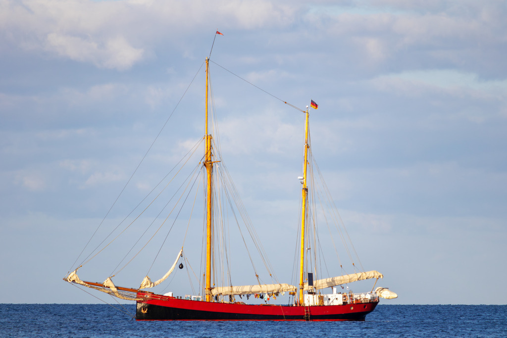 Wandbild: Traditionssegeler auf der Ostsee | Dieses Wandbild im Querformat fängt die romantische Stimmung eines Abends auf der Ostsee ein. Ein Traditionssegler segelt vor Weidefeld, während der stark bewölkte Himmel und das Licht der Abendsonne eine faszinierende Szenerie schaffen. Holen Sie sich dieses stimmungsvolle maritime Kunstwerk nach Hause und genießen Sie die ruhige Schönheit der Küste. - Realisiert mit Pictrs.com