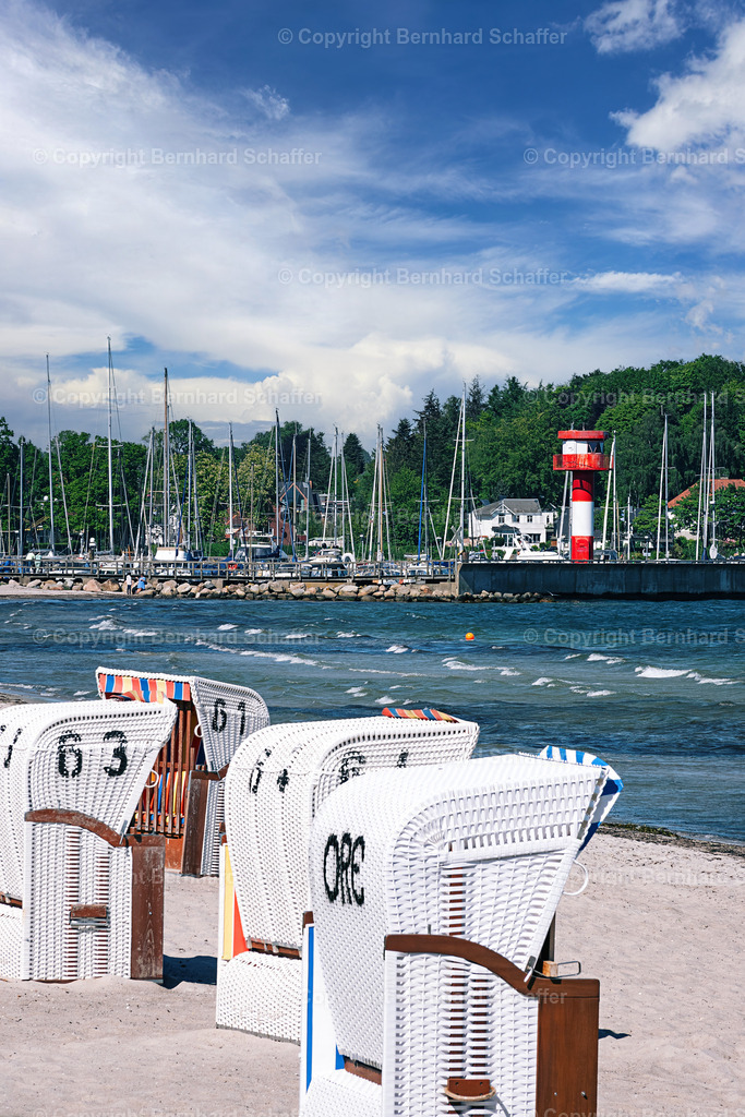 Strandstyle in Eckernförde | Mehrere weiße Strandkörbe und ein Leuchtturm am Ostseestrand im Hafen von Eckernförde in Deutschland.  - Realisiert mit Pictrs.com