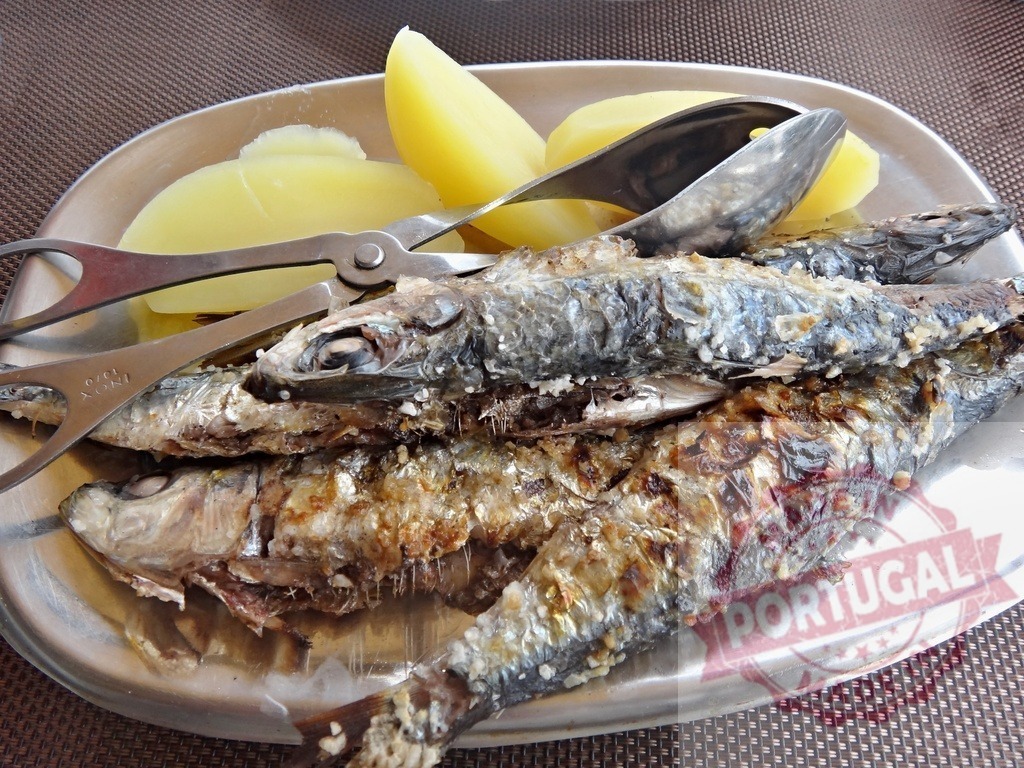 Grilled sardines and potatoes serving on metal plate | Cooked sardines with boiled potatoes and tongs on a silver plate - Realized with Pictrs.com
