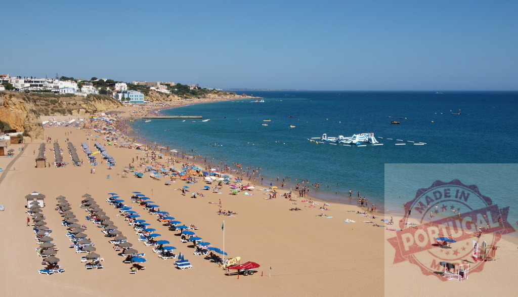 Albufeira beach in Portugal full of summer vacation tourists | Crowded beach with sunbathers, swimmers, and waterpark in Albufeira, Portugal - Realized with Pictrs.com
