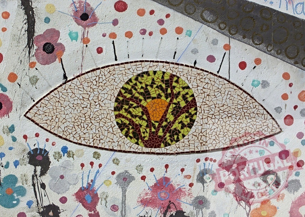 Mosaic eye looking at abstract colorful blooming flower wall art | Mosaic eye with tree pupil watches over abstract painted flowers creating vibrant wall art - Realized with Pictrs.com