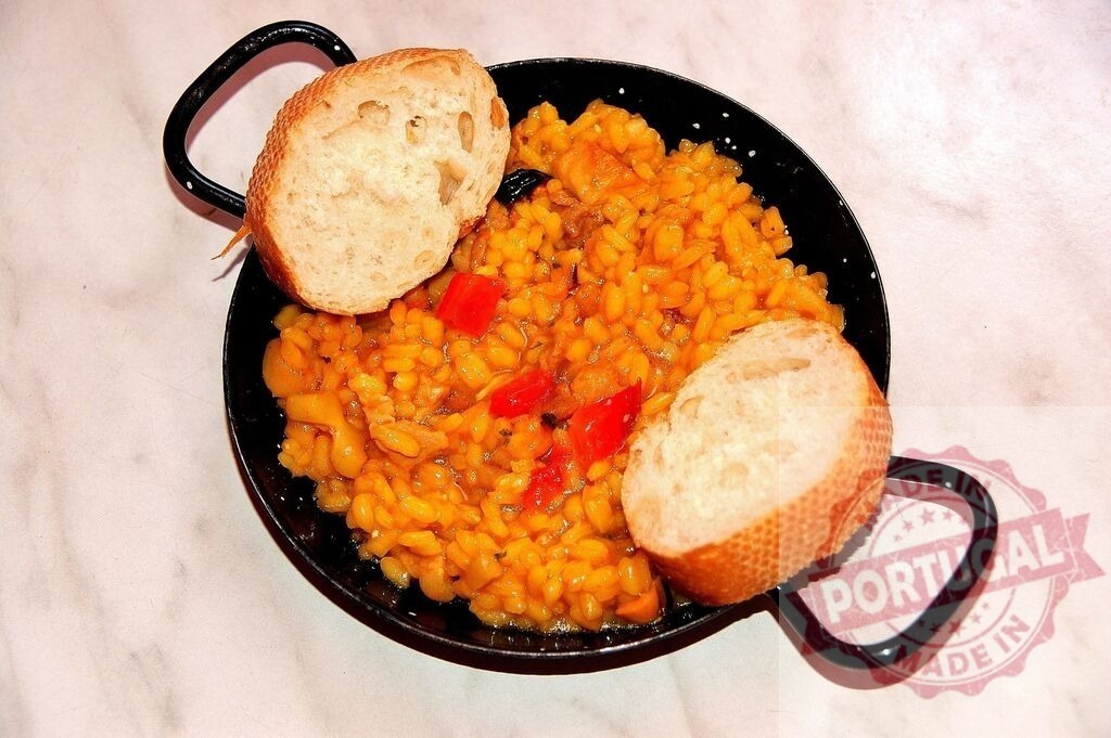 Spanish paella in pan with bread slices | Traditional Spanish paella with rice, seafood, and vegetables served in a black pan - Realized with Pictrs.com
