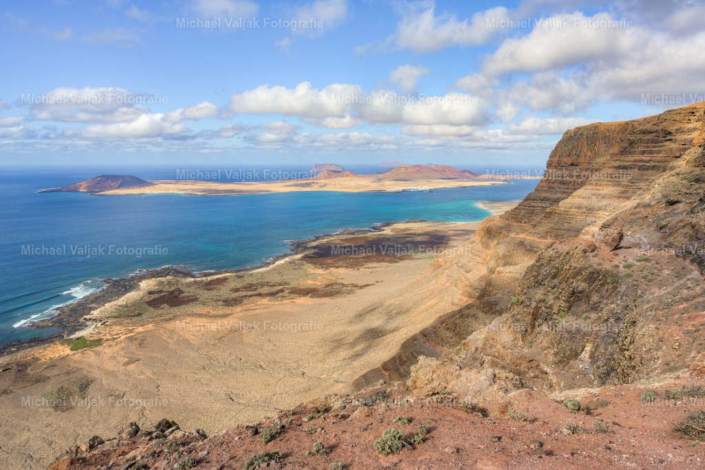Mirador de Guinate auf Lanzarote | Der Mirador de Guinate zählt zu den eindrucksvollsten Aussichtspunkten im Norden der Insel. Von hier schweift der Blick über die zerklüftete Küste, hinaus auf den Atlantik und hinüber zu den Inseln des Chinijo-Archipels. Besonders markant erscheinen die steilen Klippen von Famara, die sich wie eine gewaltige Wand am Horizont erheben. - Realisiert mit Pictrs.com