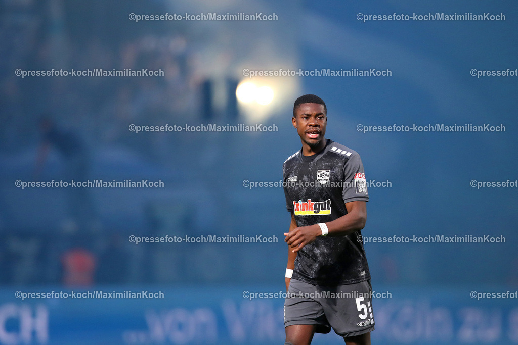 Koe3Liga17042301034 | 17.04.2023, Köln, Fußball, bwin 3. Liga Herren, Sportpark Höhenberg, 32. Spieltag, Saison 2022 2023, FC Viktoria Köln – MSV Duisburg: Leroy Kwadwo von MSV Duisburg vor den blauen Rauchwolken. Ultras brennen im Hintergrund Bengalisches Feuer ab. DFB regulations prohibit any use of photographs as image sequences and or quasi-video.