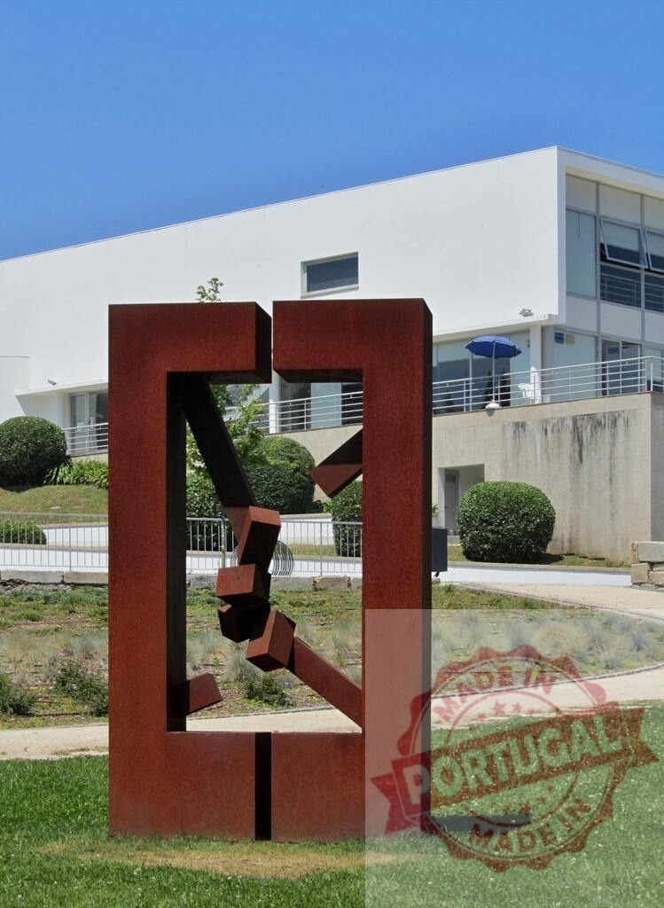 Rusty corten steel geometric outdoor garden sculpture. Portugal - Norte | Abstract modern art sculpture standing in a green park with a white building - Realized with Pictrs.com