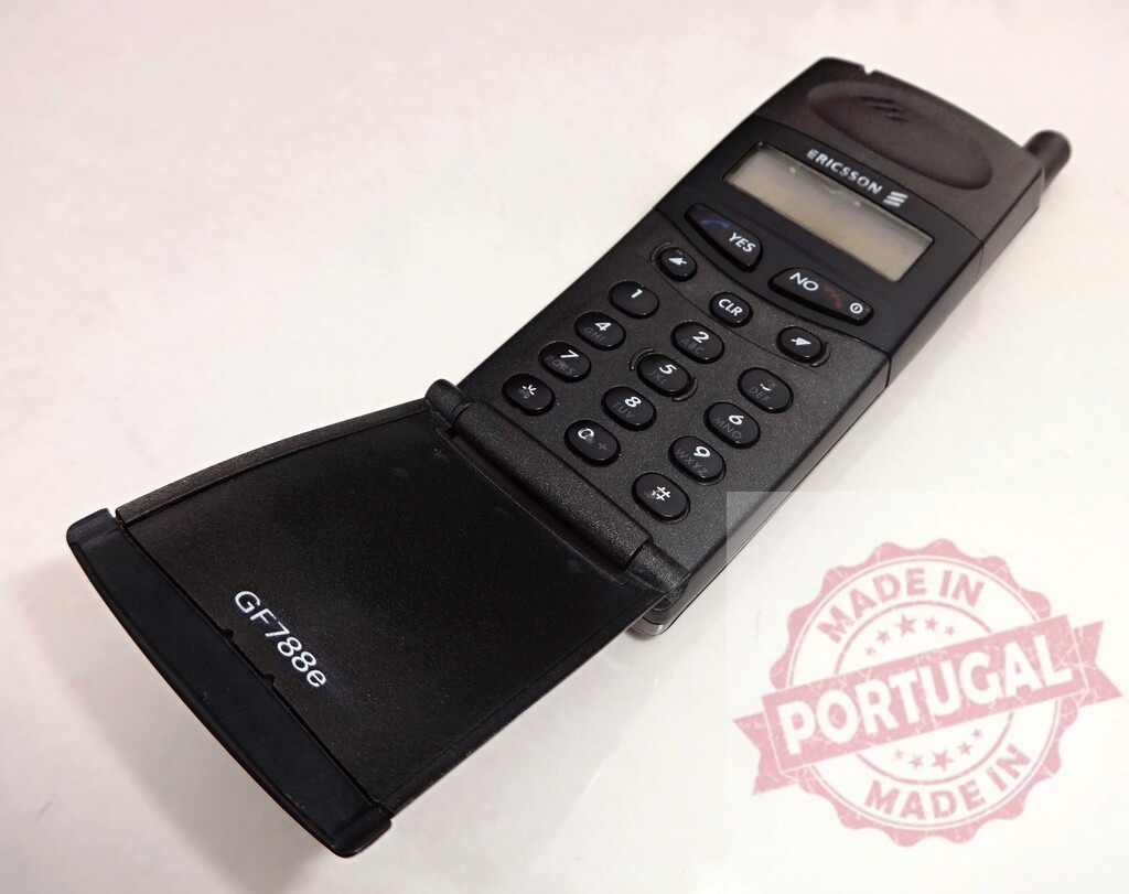 Ericsson GF788e mobile phone showing keypad and flip cover | Vintage Ericsson GF788e cell phone lying open on a white background, showcasing its keypad and flip cover - Realisiert mit Pictrs.com