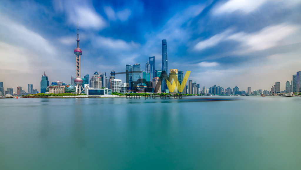 Eine Langzeitbelichtung der Skyline von Shanghai-Oriental Pearl Tower | Das Bild zeigt die Skyline von Shanghai, China, aufgenommen vom Bund aus über den Huangpu-Fluss. Die markante Skyline zeigt das Finanzviertel Lujiazui.Zu den prominenten Gebäuden gehören der Oriental Pearl Tower (links mit der Kugel), der Shanghai Tower (höchstes Gebäude in der Mitte) und das Shanghai World Financial Center (mit der trapezförmigen Öffnung).Die Langzeitbelichtung des Fotos lässt die Wolken verschwommen erscheinen und glättet die Wasseroberfläche. - Realisiert mit Pictrs.com