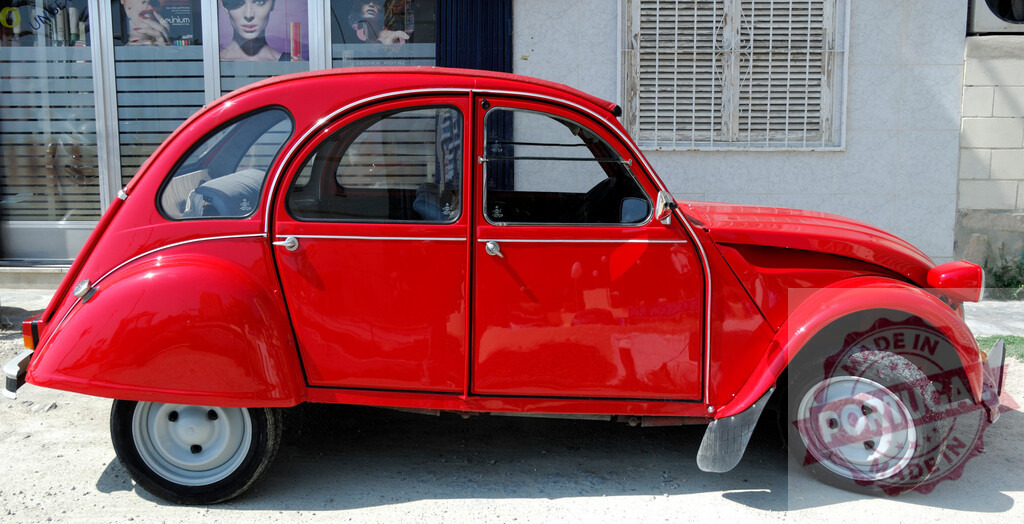 Shiny red Citroën 2CV parked on the street | Classic red Citroën 2CV parked near a store window displaying beauty products - Realisiert mit Pictrs.com