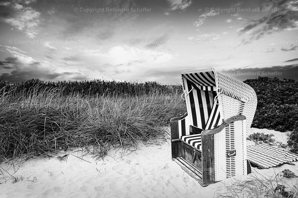 Strandkorb in den Dünen | Ein einzelner Strandkorb steht im Sand in den Dünen an der Ostsee - schwarz-weiss. - Realisiert mit Pictrs.com