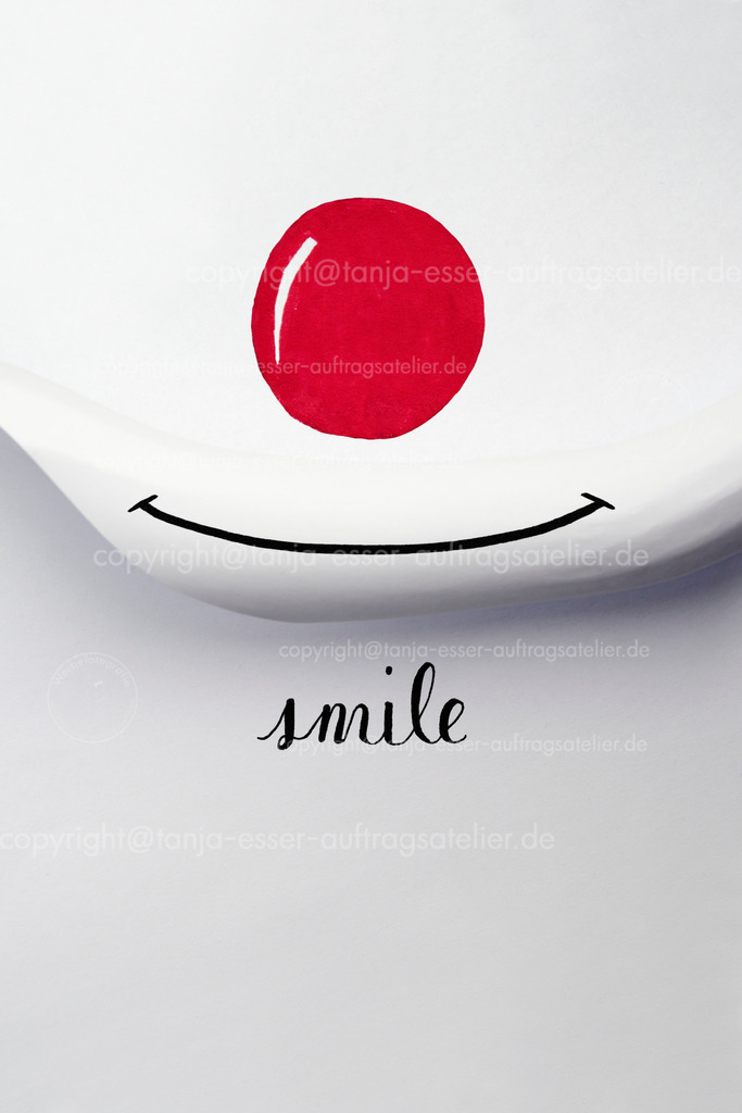 Smile gerolltes Papier | Ein Blatt gerolltes weißes Papier vor einem weiteren Blatt Papier bildet einen lächelnden Mund eines Clown. Rote gemalte runde Clownnase. Englischer Text: Smile