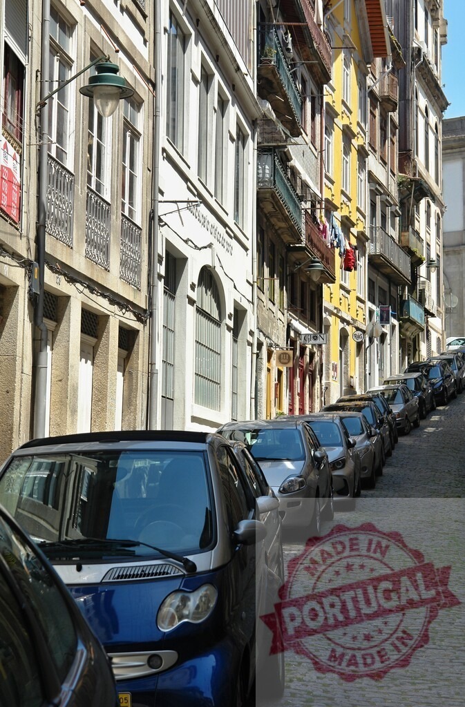 Porto city street with parked cars on a cobblestone hill | Cars parking on a steep cobblestone street bordered by classic Porto architecture - Realized with Pictrs.com