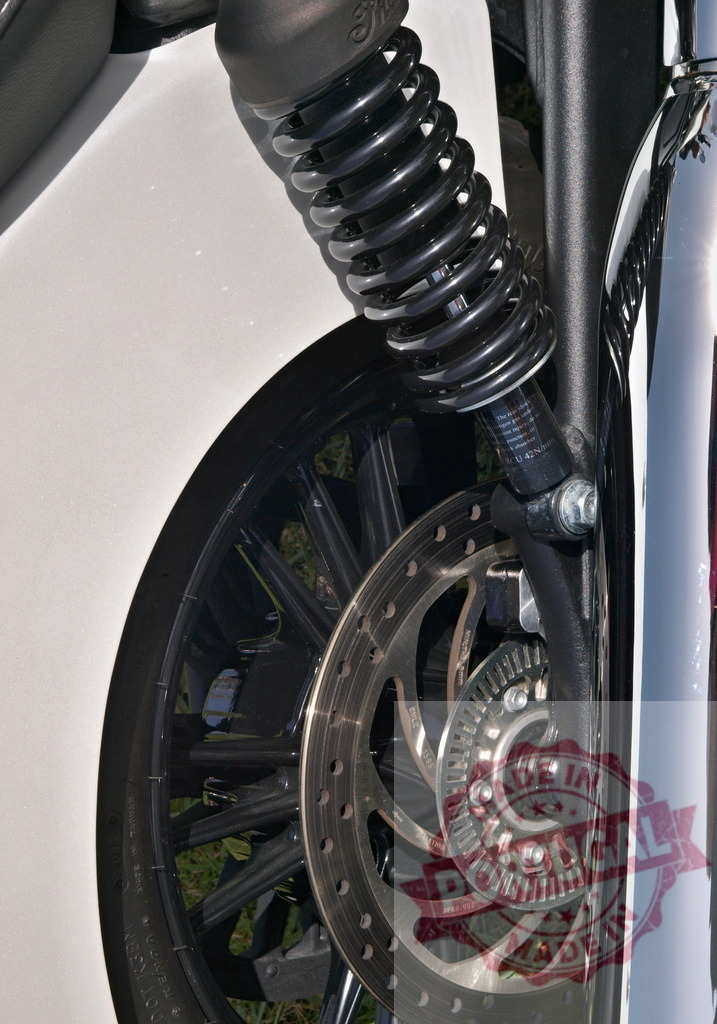 Motorcycle wheel displaying suspension shock absorber and brake disc | Motorcycle wheel showing shock absorber, coil spring, brake disc, and tire - Realized with Pictrs.com