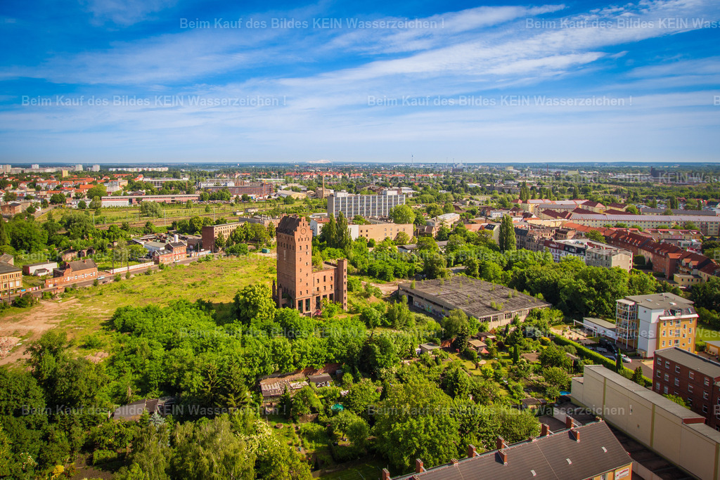 Magdeburg Alte Bodenstein Brauerei Sieverstorstraße Neustadt-5965 | Im Mittelpunkt dieser Luftaufnahme steht der erhaltene Sudturm der ehemaligen Brauerei Bodenstein an der Sieverstorstraße in der Alten Neustadt. Der markante Backsteinturm erinnert an ein bedeutendes Kapitel der Magdeburger Brauereigeschichte. Rund um das Gebäude erstrecken sich heute bewachsene Freiflächen, Gärten und neuere Bebauung. Vom einstigen Brauereigelände ist nur noch ein kleiner Teil der historischen Anlage erhalten geblieben. –  – August Leberecht Bodenstein gründete seine Brauerei am 8. August 1823. Nach der Enteignung in der Nachkriegszeit wurde der Betrieb als VEB Börde-Brauerei weitergeführt. 1991 endete die Bierproduktion; in den folgenden Jahren wurden große Teile des Geländes abgerissen. Der 1936 errichtete Sudturm blieb als sichtbares Zeugnis der früheren Nutzung bestehen. –  – Die Aufnahme zeigt, wie sich das ehemalige Industrieareal in das heutige Umfeld der Alten Neustadt einfügt. Zwischen Wohnhäusern, Grünflächen und Gewerbebauten steht der Turm als markanter Orientierungspunkt und erinnert an die lange Industriegeschichte dieses Stadtteils. - Realisiert mit Pictrs.com