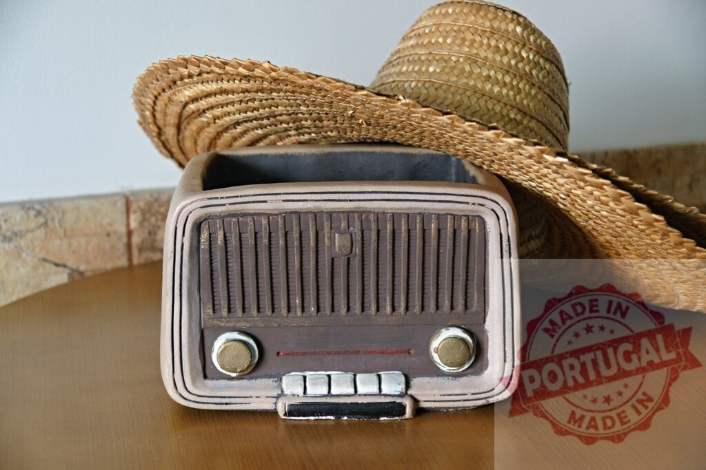 Two straw hats resting on a vintage radio shaped flower pot on a wooden table | Two straw hats are lying on a vintage radio shaped flower pot, evoking a nostalgic summer atmosphere - Realisiert mit Pictrs.com
