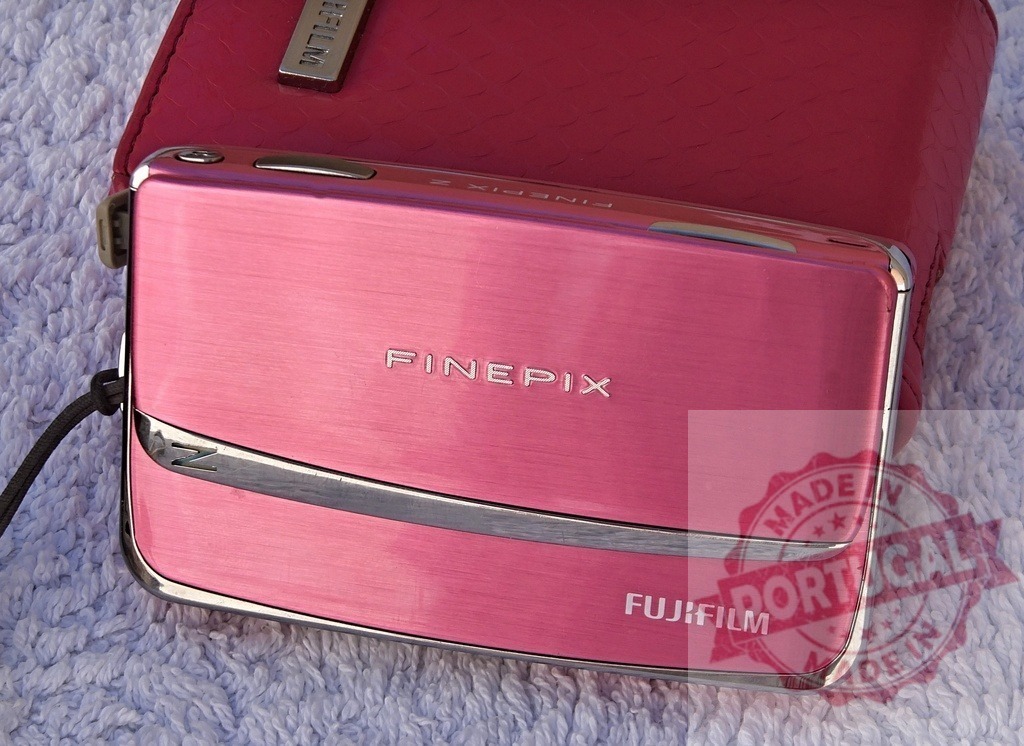 Fujifilm FinePix Z pink compact digital camera on white towel | Pink Fujifilm FinePix Z digital camera displaying its design and branding on a soft white surface - Realized with Pictrs.com