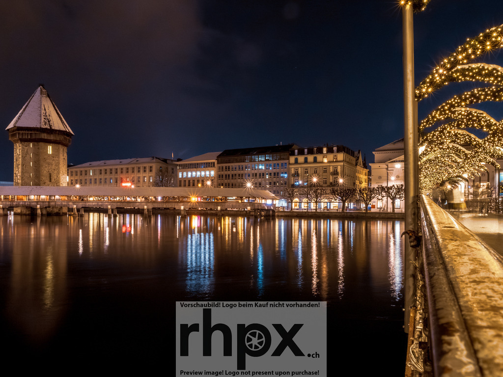 Kapellbrücke & Winterlichter Luzern | Geschichte. Reflexion. Lichterglanz.Die weltberühmte Kapellbrücke ruht majestätisch über der dunklen Reuss, während festliche Lichterbögen den Weg säumen. Eine stimmungsvolle Winternacht, die das historische Herz der Schweiz in stiller Eleganz einfängt.Wähle unter "Produktauswahl" dein Wunschformat: Vom klassischen Wandbild über Puzzle &amp; Tassen bis zum digitalen Download (z.B. als Handy-Hintergrund). - Realisiert mit Pictrs.com