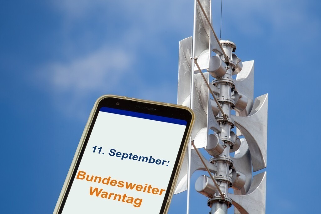 Bundesweiter Warntag 11. September: Sirene und Smartphone | (Fotomontage) Nahaufnahme einer Sirene, daneben ein geöffnetes Smartphone mit Text 11. SEPTEMBER: BUNDESWEITER WARNTAG - Realisiert mit Pictrs.com