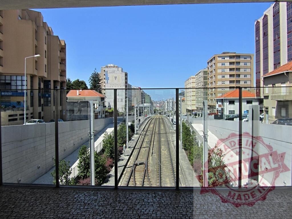 Urban railway tracks through modern city landscape. Norte - Portugal | Railway tracks extend through a modern urban setting surrounded by buildings under clear blue sky - Realized with Pictrs.com