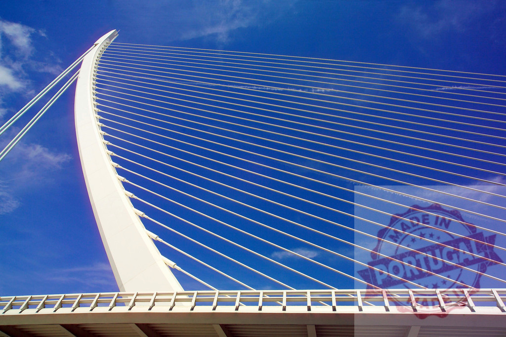 Modern white cable-stayed bridge rising towards a deep blue sky | Low angle view of a modern white cable-stayed bridge against a deep blue sky, showcasing architectural design and engineering - Realized with Pictrs.com