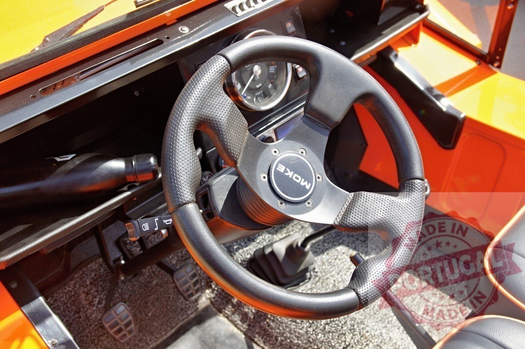 Moke car interior with steering wheel and manual transmission | Orange Moke car interior showing a steering wheel, dashboard, and manual gear stick - Realized with Pictrs.com