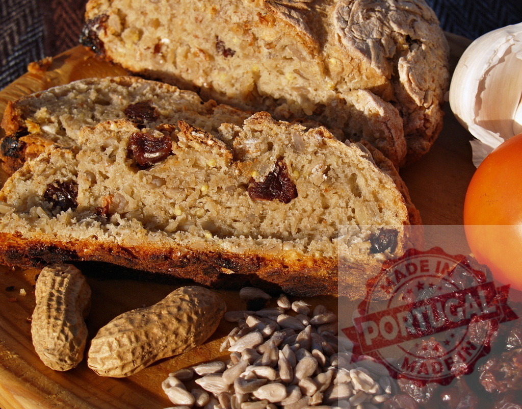 Sliced rustic bread with raisins and seeds | Healthy homemade bread loaf on a wooden cutting board with raw ingredients - Realisiert mit Pictrs.com