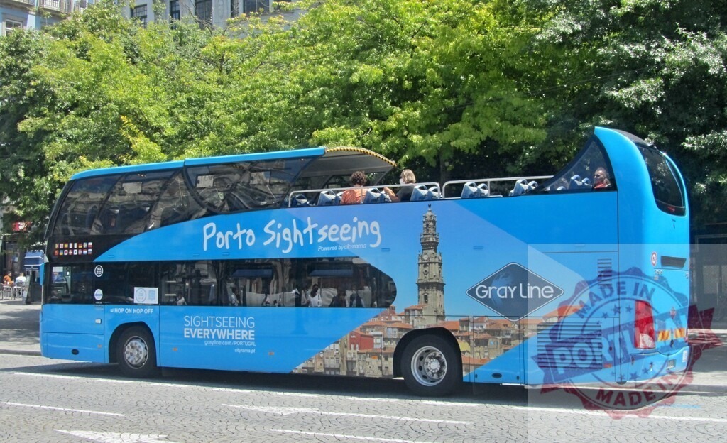 Gray Line Porto sightseeing double-decker bus transporting tourists | Blue Gray Line open-top bus moving through Porto, Portugal, on a sunny day - Realized with Pictrs.com