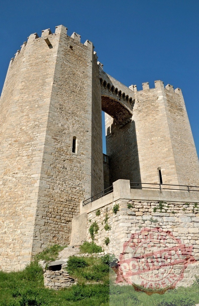 Aigues-Mortes medieval towers and connecting bridge | Historic stone fortification connecting two battlements with a walkway under a clear sky - Realized with Pictrs.com