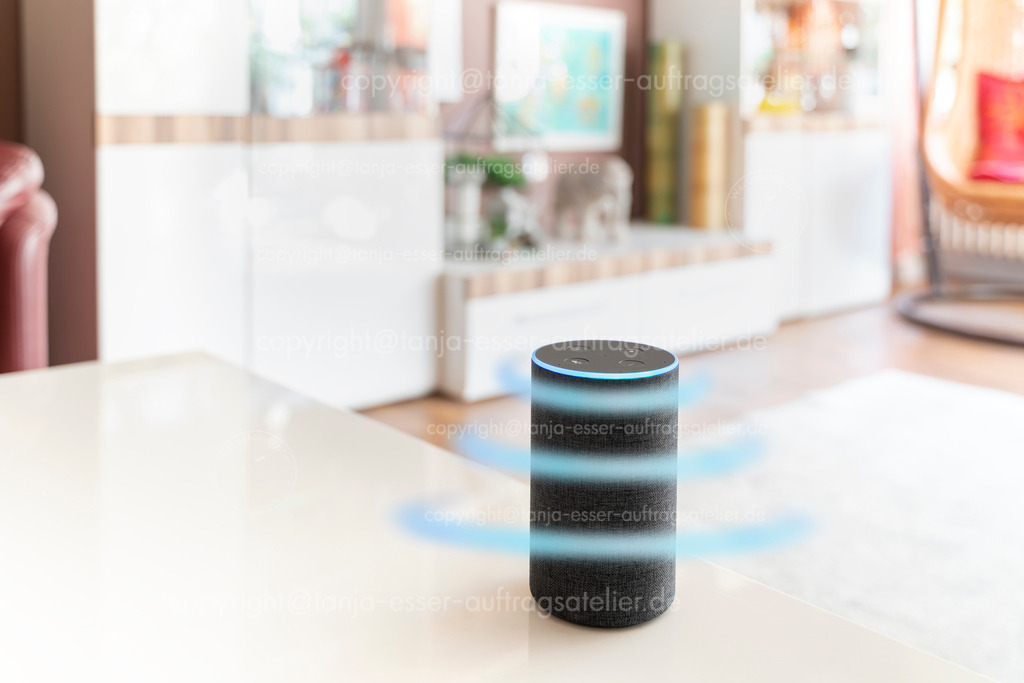 Smartes Gerät auf Empfang | Ein smarter Lautsprecher Assistent steht in einem hellen Wohnzimmer. Hellblaue Kreise symbolisieren die ausweitende Wirkung von Mikrofon oder Fernsteuerung. Viel Copy Space.