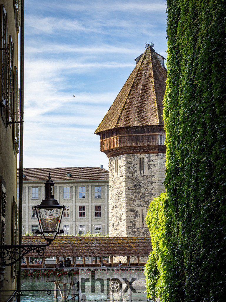 Kapellbrücke Luzern – Blick durch die Altstadtgasse | Aufnahme aus der Luzerner Altstadt mit Sicht auf die Kapellbrücke und den Wasserturm. Das enge Gassenbild mit den begrünten Hausfassaden zeigt den historischen Charakter der Stadt. - Realisiert mit Pictrs.com