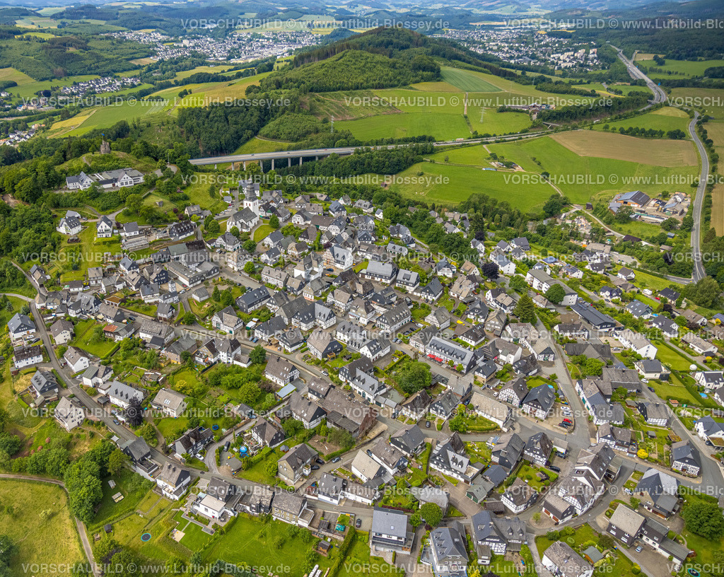 Meschede220601080 | Luftbild, Historischer Ortskern Eversberg mit Rathaus und Altes Feuerwehrgerätehaus mit Turm, Fachwerkhäuser und Kirche St. Johannes Evangelist, im Hintergrund die Schützenhalle Schlossberghalle Eversberg und Ruine der Burg Eversberg sowie die Autobahnbrücke der A46, Eversberg, Meschede, Sauerland, Nordrhein-Westfalen, Deutschland