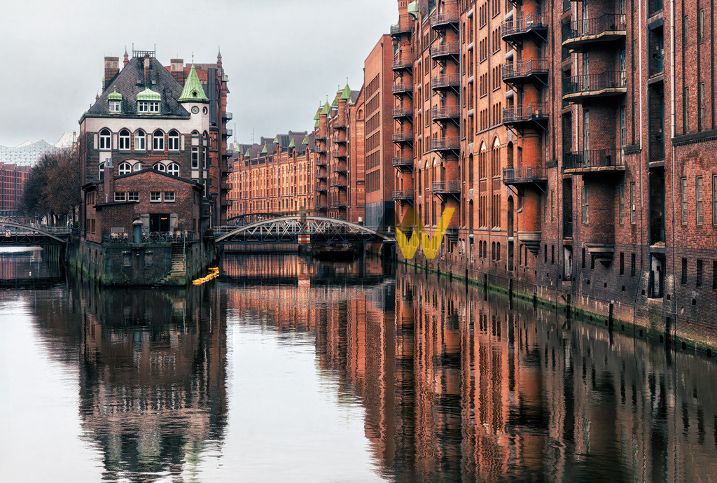 Das beliebte Wasserschloss in der Hamburger Speicherstadt | Das Bild zeigt das Wasserschloss in der Hamburger Speicherstadt. Es ist das beliebteste und meistfotografierte Motiv in diesem UNESCO-Weltkulturerbe-Gebiet. Das Gebäude wurde zwischen 1905 und 1907 am Zusammenfluss des Holländischbrook- und Wandrahmfleets errichtet. Es ist eines der zentralen Bauwerke des dritten Bauabschnitts der Speicherstadt. Heute beherbergt das denkmalgeschützte Gebäude ein Teekontor und ein Restaurant.  - Realisiert mit Pictrs.com