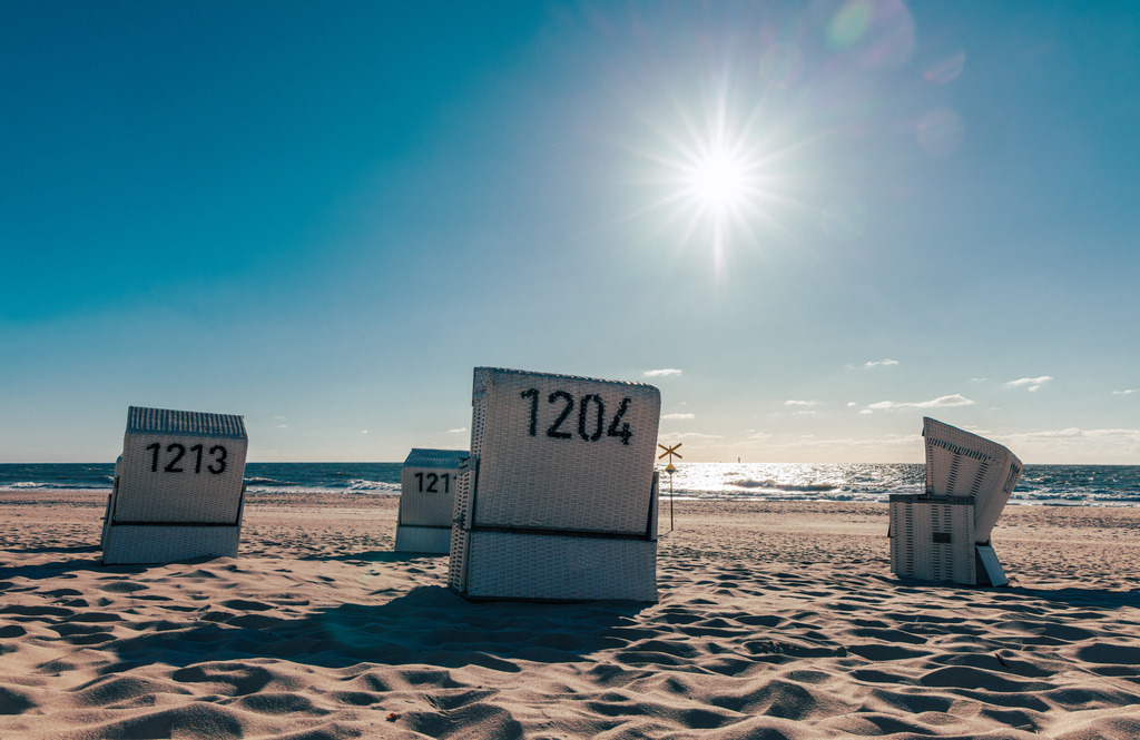 Strandkörbe am sonnigen Strand von Westerland in Sylt-Meer | Diese Strandkörbe befinden sich auf Sylt. Die Insel bietet fast 40 Kilometer feinsten Sandstrand.Die Westküste hat besonders viele Strandkörbe, die zum Sonnenbaden einladen.Diese spezifische Aufnahme zeigt Strandkörbe an einem Nordseestrand auf Sylt. - Realisiert mit Pictrs.com