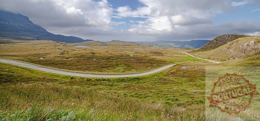 Scottish Highlands landscape with winding road and mountains | Winding road travels through remote Scottish Highlands landscape with cloudy sky - Realized with Pictrs.com